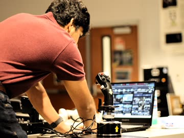 Researcher adjusting sensors beside a laptop during an interactive demonstration
