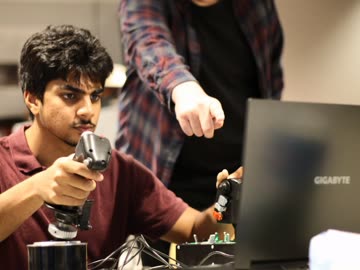 Researcher adjusting sensors beside a laptop during an interactive demonstration