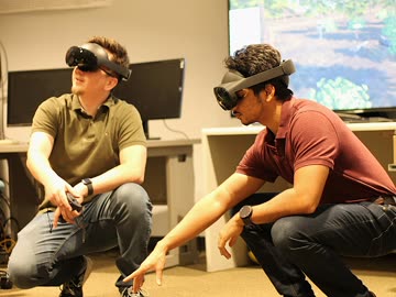 Two researchers wearing head-mounted displays collaborating in VR