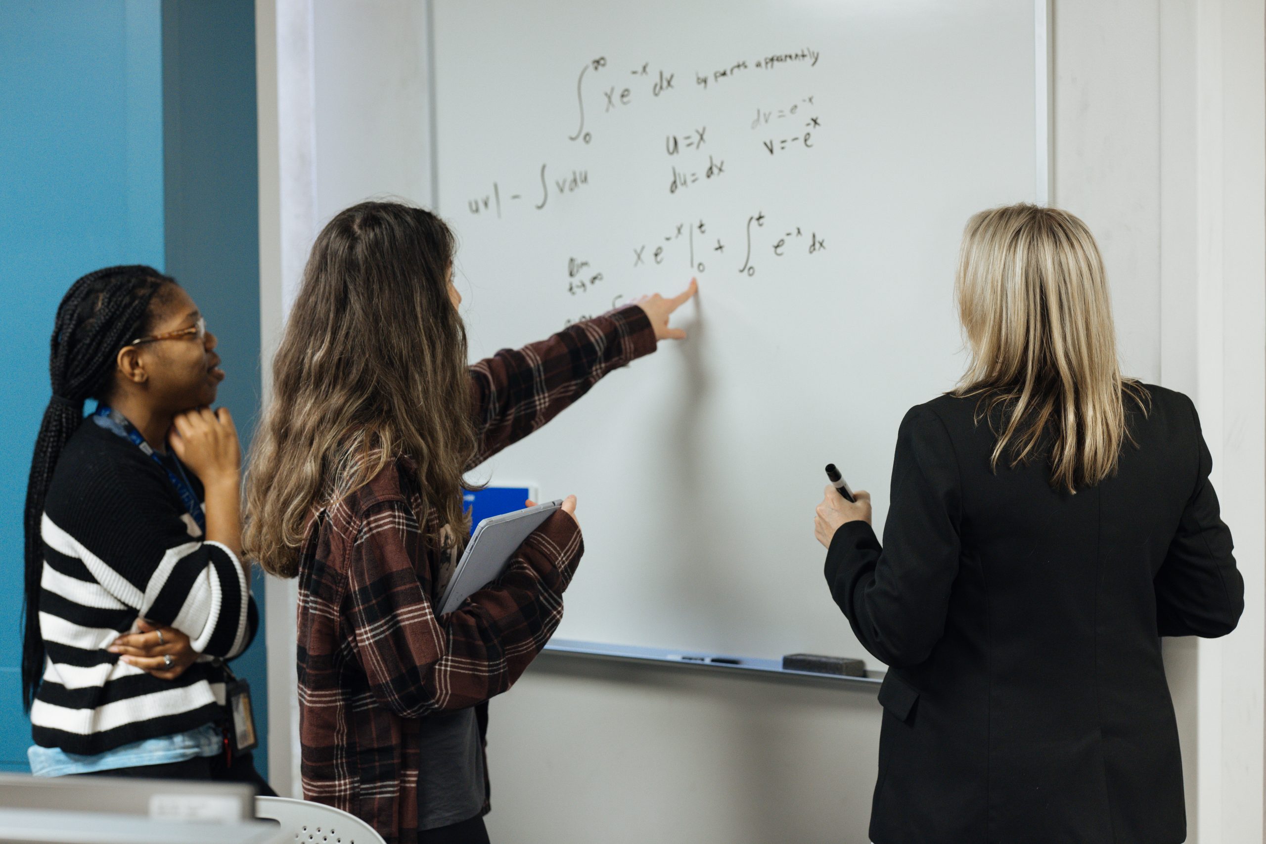 people writing numbers in front of white board
